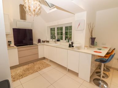 A kitchen with white cabinets a stove and a sink under a window at Hiraeth in Cwmtaf near Cefn-Coed-Y-Cymmer