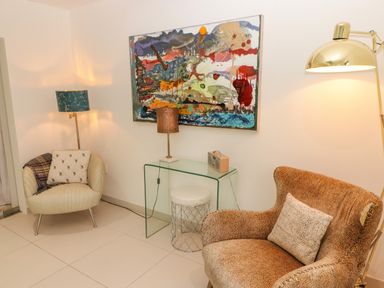 A sitting area with two armchairs a glass side table with a lamp and radio and a painting on the wall at Hiraeth in Cwmtaf near Cefn-Coed-Y-Cymmer