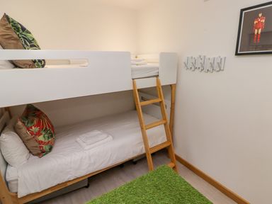 A bunk bed with pillows and towels a ladder a green rug and a framed picture on the wall at Hiraeth in Cwmtaf near Cefn-Coed-Y-Cymmer