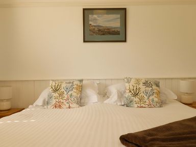 A bedroom with a bed and decorative pillows at Pentreath in Crantock