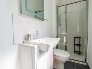 A bathroom with sink, toilet, shower and storage shelf at Pentreath in Crantock