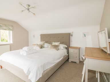 A bedroom with a large bed and bedside tables at The Orchard in Crantock