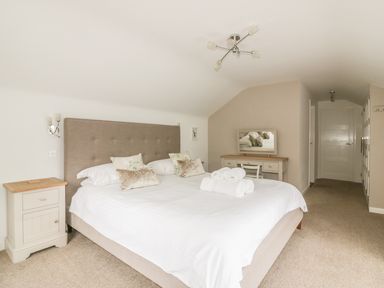 A bedroom with a large bed and a side table at The Orchard in Crantock