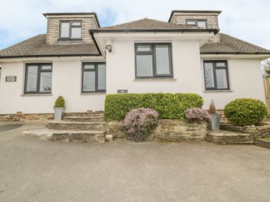 The exterior of a house with stone steps shrubs and plants at The Orchard in Crantock