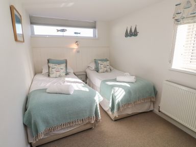 A bedroom with two single beds side by side with blue blankets and patterned pillows at Kittiwake in Crantock