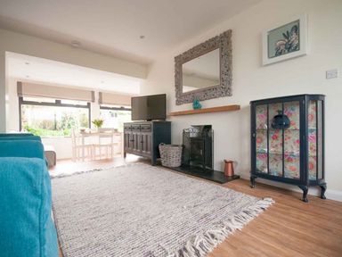 A living room with a blue cabinet and a dining area in the background at Keelyn in Crantock
