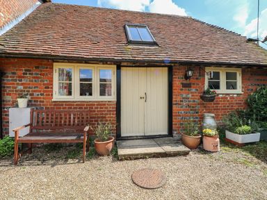 Exterior view of a brick building with a bench and potted plants near the door at Downs View Dairy in West Tytherley