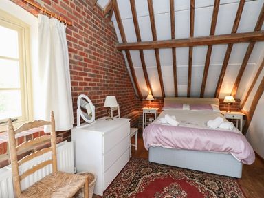 A bedroom with a double bed two bedside tables with lamps a white dresser and a wooden chair at Downs View Dairy in West Tytherley
