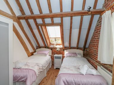 A bedroom with two single beds a skylight window wooden floor and exposed wooden beams at Downs View Dairy in West Tytherley