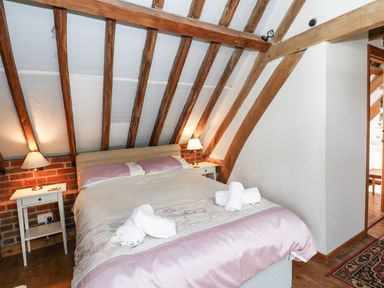 A bedroom with a double bed two bedside tables with lamps and wooden ceiling beams at Downs View Dairy in West Tytherley