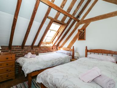 A bedroom with two single beds under a sloped ceiling with exposed wooden beams and a skylight window at Downs View Dairy in West Tytherley