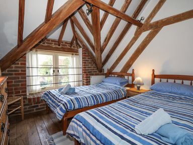 A bedroom with two single beds with striped bedding under wooden beams at Downs View Dairy in West Tytherley