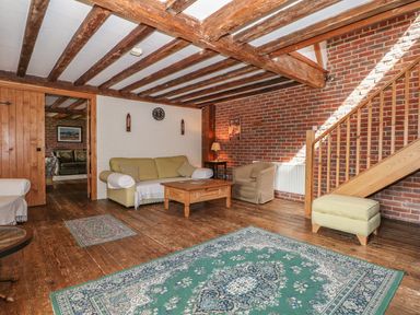 A living room with sofas a wooden coffee table and a staircase at Downs View Dairy in West Tytherley