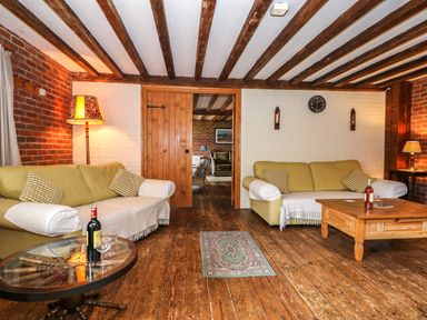 A living room with wooden beams on the ceiling two sofas and a coffee table at Downs View Dairy in West Tytherley