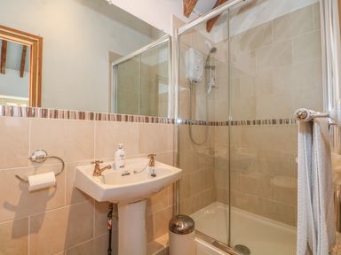 A bathroom with a shower enclosure a pedestal sink a large mirror and a towel rack at Downs View Dairy in West Tytherley