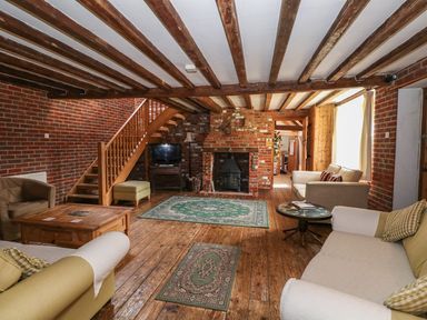 A living room with wooden beams on the ceiling a brick fireplace wooden floor and sofas at Downs View Dairy in West Tytherley