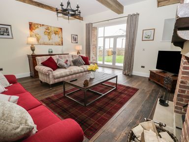 A living room with a sofa, coffee table, and television at The Turnip Barn in 