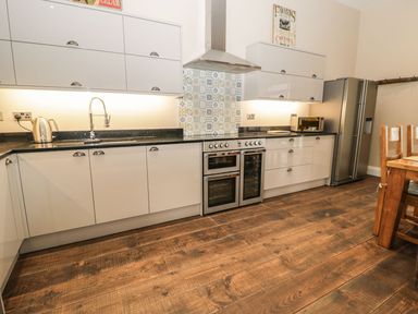 A kitchen with cabinets, sink, kettle, cooker and refrigerator at The Turnip Barn in 