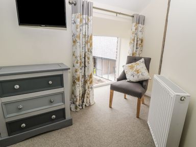 A bedroom with a television, dresser, chair and curtains at The Turnip Barn in 