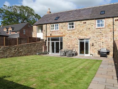 A garden with stone wall and patio furniture at The Turnip Barn in 