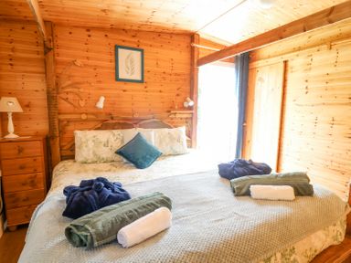 A bedroom with a large bed with folded towels and robes on it at Brook Lodge in Penrhiwllan