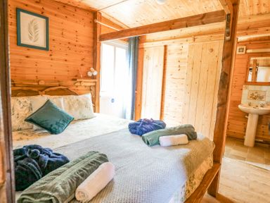 A wooden bedroom with a four-poster bed and towels on the bed at Brook Lodge in Penrhiwllan
