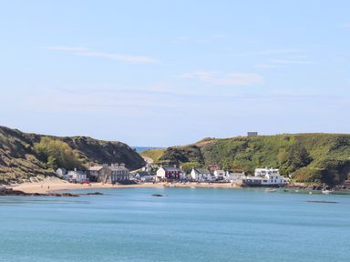 A coastal village with houses on a sandy beach surrounded by green hills and blue water at Tan Y Goeden in Morfa Nefyn