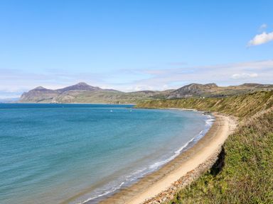 A sandy beach with a curved shoreline and hills in the background at Tan Y Goeden in Morfa Nefyn