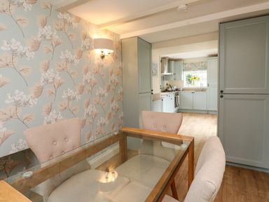 A dining room with a table and chairs leading to a kitchen at Tan Y Goeden in Morfa Nefyn