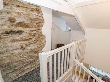 A stairway with white railing next to a stone wall and a small sitting area at Pentowyn in Holyhead