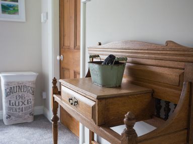 A wooden hall stand with a drawer and a green metal container next to a laundry basket in a room at Moelwyn View Cottage in Llan Ffestiniog