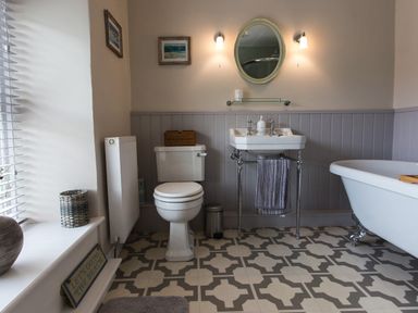 A bathroom with a toilet sink bathtub wall mirror and patterned floor tiles at Moelwyn View Cottage in Llan Ffestiniog