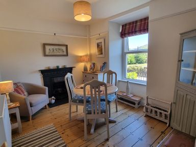 A dining room with a round table and four chairs next to a window and a fireplace at Moelwyn View Cottage in Llan Ffestiniog