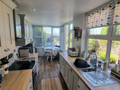 A kitchen with cabinets a sink a toaster a microwave a stove and a small dining table with chairs at Moelwyn View Cottage in Llan Ffestiniog