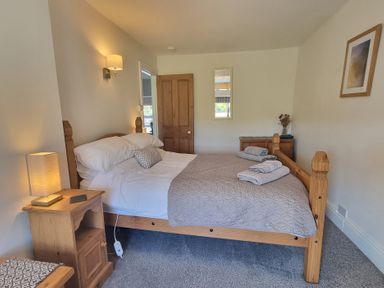 A bedroom with a wooden bed and side table with a lamp at Moelwyn View Cottage in Llan Ffestiniog