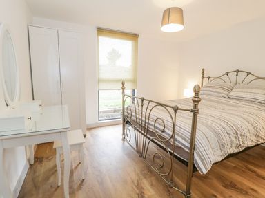 A bedroom with a metal bed frame and striped bedding a white wardrobe and a white dressing table with a mirror at Swan Lodge Castle Farm in Wedmore