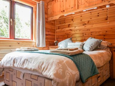 A bedroom with a bed and folded towels and pillows in Oak Lodge Constantine near Falmouth