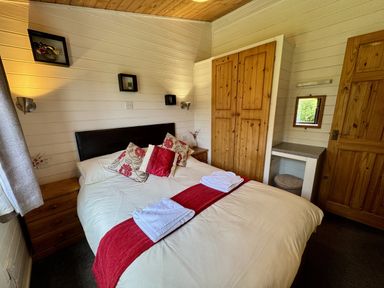 A bedroom with a bed and wardrobe at Willow Lodge in Constantine near Falmouth