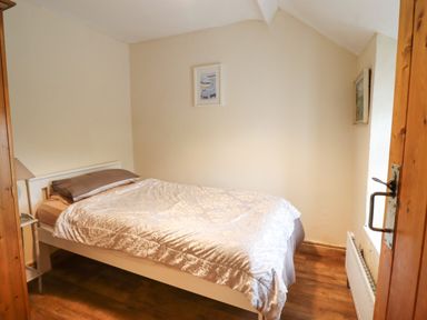 A bedroom with a single bed a bedside table and radiator at Gwenallt in Malltraeth