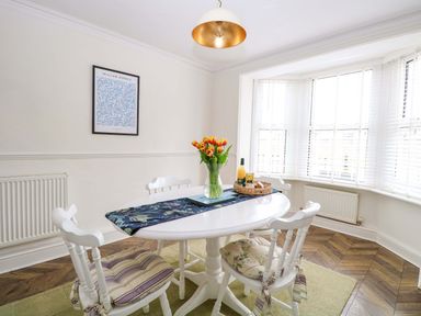 A dining room with a table, chairs, and a vase of tulips at Springfield in Hempton near Fakenham