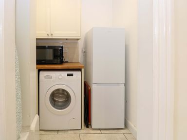 A utility room with washing machine refrigerator and microwave at Springfield in Hempton near Fakenham
