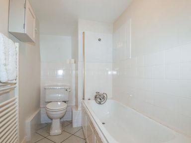 A bathroom with a toilet, bathtub, towel rail, and wall cabinet at Lanvean Farmhouse in Lanvean near St Mawgan