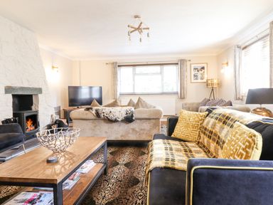 A living room with sofas a wooden coffee table a fireplace and a television at Coed Derw Isaf in Betws-Y-Coed