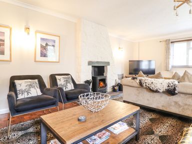 A living room with two chairs a coffee table a fireplace a sofa and a television at Coed Derw Isaf in Betws Y Coed