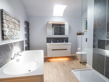 A bathroom with a bathtub a sink with two faucets a mirror a toilet and a shower at Coed Derw Isaf in Betws-Y-Coed