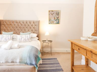 A bedroom with a bed a bedside table with a lamp a rug a wooden desk and a framed picture on the wall at Coed Derw Isaf Betws-Y-Coed