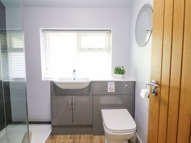 A bathroom with a sink and toilet under a window with blinds at Coed Derw Isaf in Betws-Y-Coed