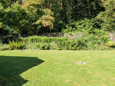 A garden with green grass and croquet equipment near a stone wall and trees at Coed Derw Isaf in Betws-Y-Coed