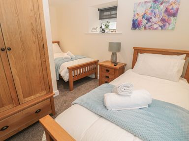 A bedroom with two single beds wooden furniture and a small window at River Cottage in Morpeth
