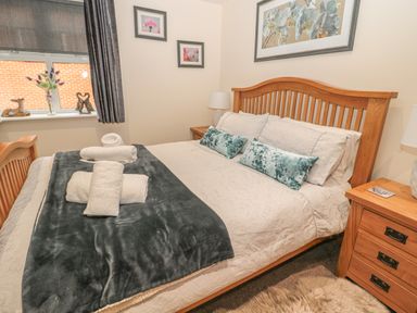 A bedroom with a wooden bed and bedside tables with lamps at River Cottage in Morpeth